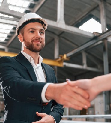 Handshake with partner. Manager in black formal wear at the factory.